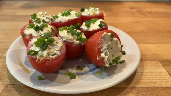 KI generiert: Gefüllte Tomaten mit einer Creme, garniert mit Frühlingszwiebeln auf einem Teller.
