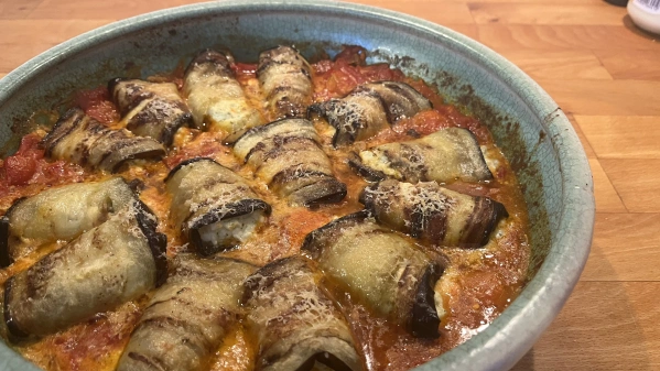 KI generiert: Eine Auflaufform mit gefüllten, gerollten Auberginenscheiben auf Tomatensauce.