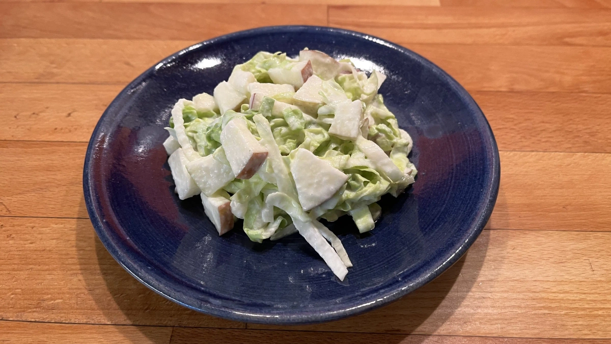 Salat mit Apfelstücken und Joghurtdressing auf blauem Teller