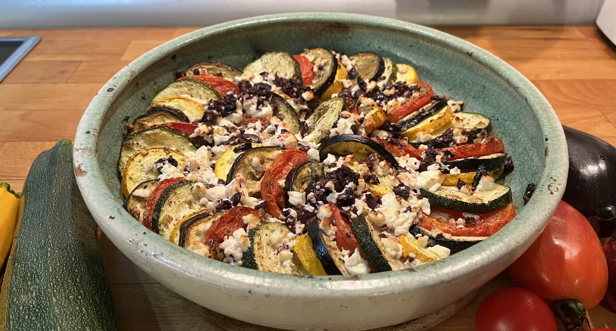 Scheiben aus Tomaten, Zucchini und Aubergine in Auflaufform überbacken mit Feta und Oliven