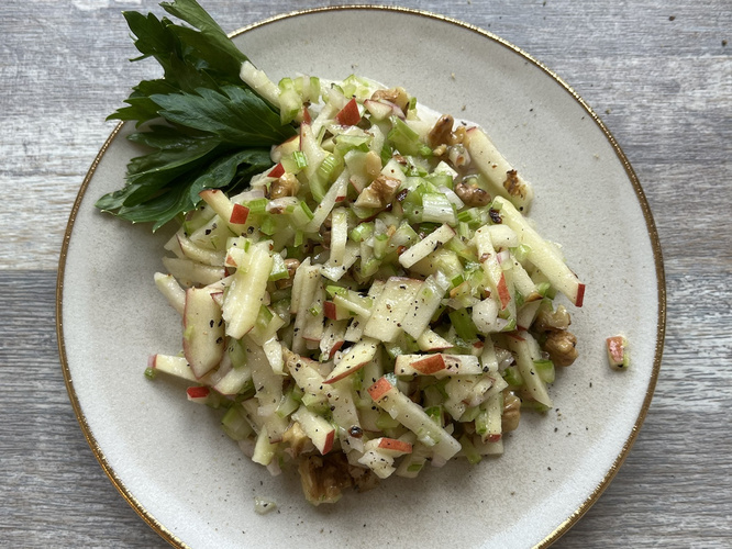 Salat aus Stangensellerie und Apfel auf weißem Teller