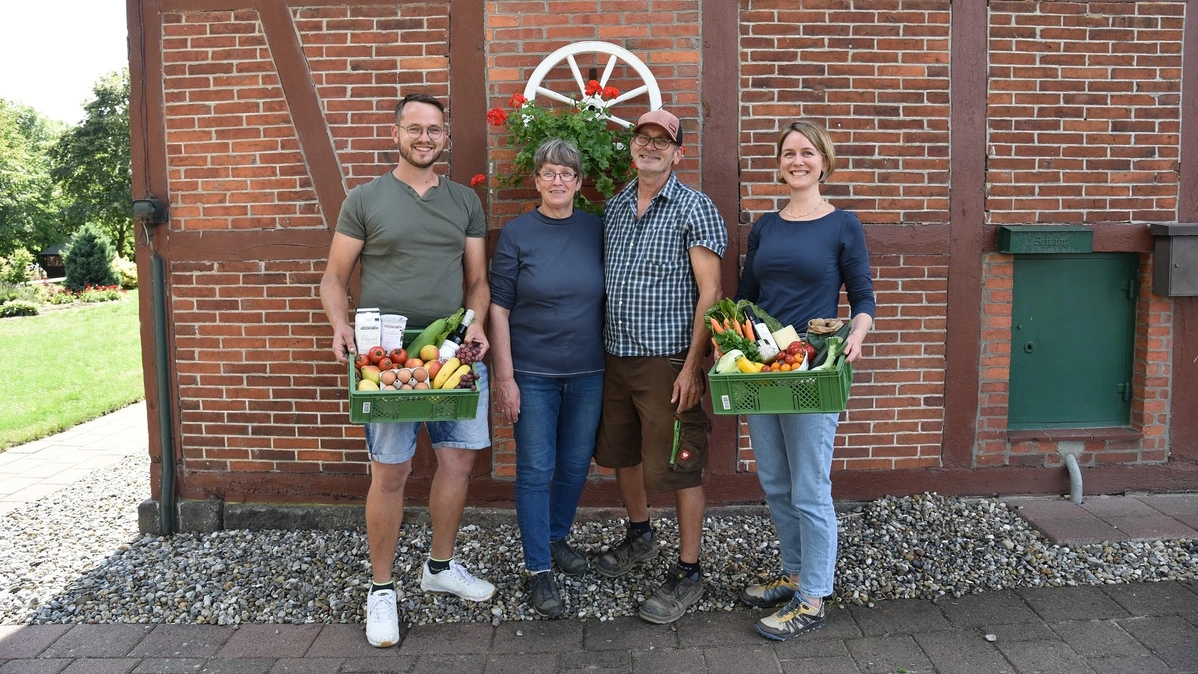 Jörg, Hjalmar, Hjördis und Hedda vor einem Fachwerkhaus mit gefüllten Biokisten