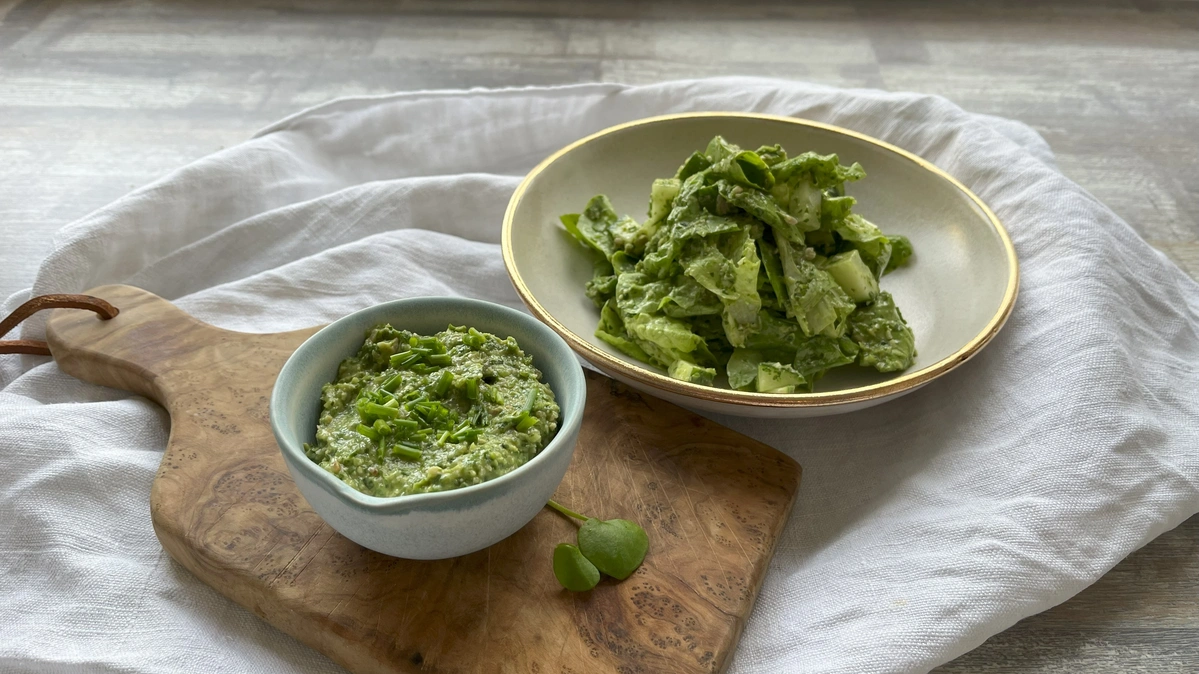 Grünes Kräuterdressing in kleiner Schale auf Holzbrett