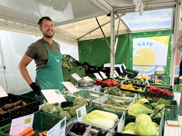 Hjalmar hinter einem Marktstand mit Biolandgemüse