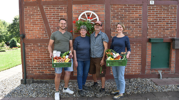 Das Führungsteam von Emmerts-Biokiste und der Gärtnerei Emmert steht vor einem Fachwerkhaus mit Biokisten in der Hand
