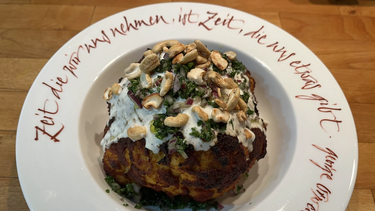 Ganzer marinierter Blumenkohl mit Toppings aus Joghurt, Petersilie und Cashewkernen auf beschriftetem Teller