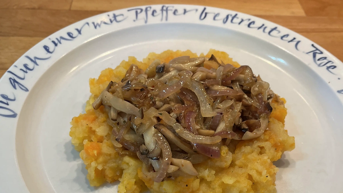 Steckrübenstampf mit Zwiebel-Pilz-Pfanne auf weißem Teller mit blauer Aufschrift