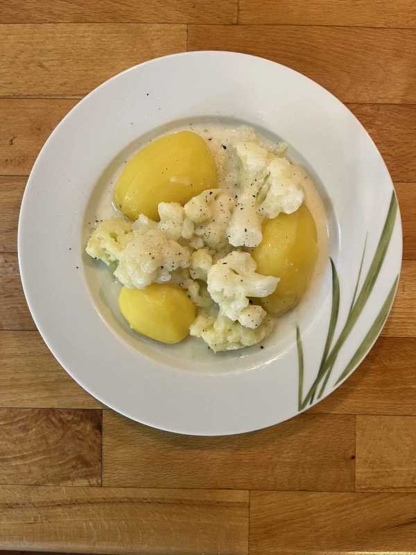 Ein Teller mit Kartoffelpüree, Zwiebeln und Tofuwürfeln. 
