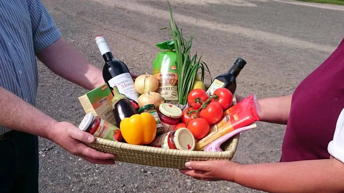 Ein Korb mit Obst, Gemüse Pasta und Wein wird überreicht.