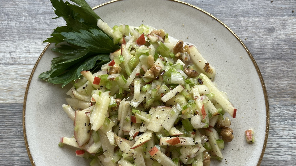 Salat aus Stangensellerie und Apfel auf weißem Teller
