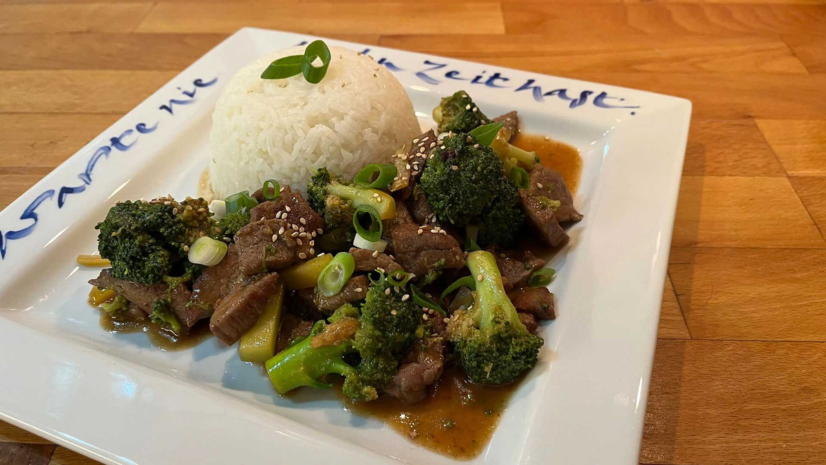 Teller mit Kartoffeln und Blumenkohl in heller Sauce auf Holzuntergrund.