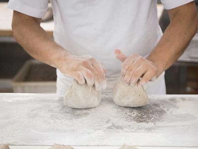 Person knetet Teig auf einer bemehlten Arbeitsfläche.