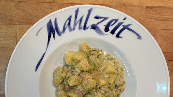 KI generiert: Ein Teller mit Kartoffelgericht, darüber steht "Mahlzeit".