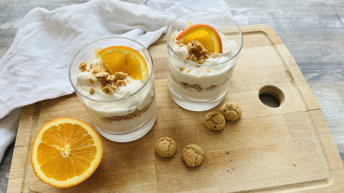 Zwei Dessertgläser mit Orangenquark auf Holzbrett