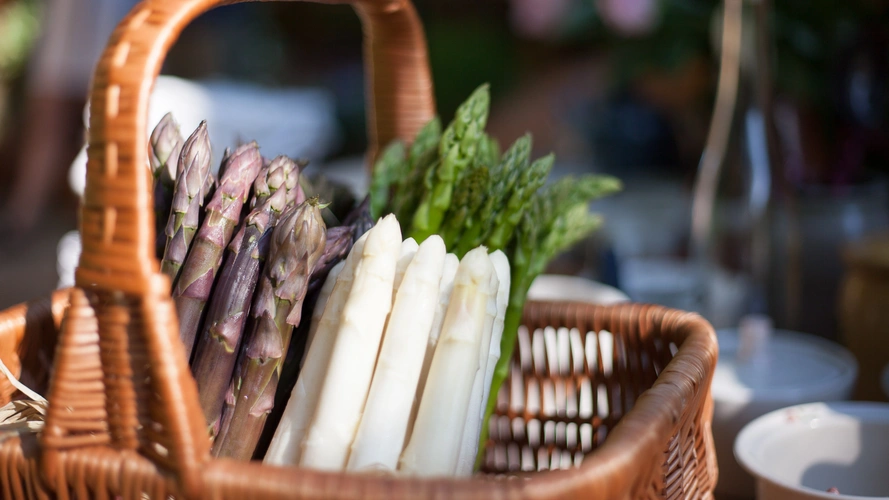 KI generiert: Ein Korb mit weißem, grünem und violettem Spargel.