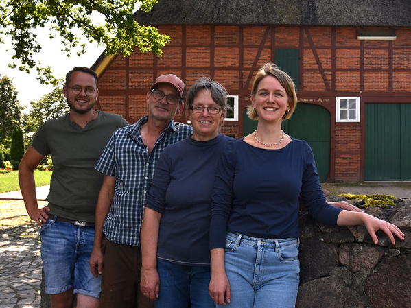 Vier Personen stehen vor einem Fachwerkhaus.