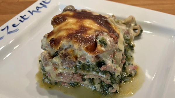 Spinatlasagne mit Hackfleisch auf weißem Teller