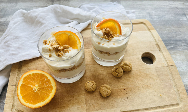 Zwei Gläser mit Orangencremedessert und Holzbrett