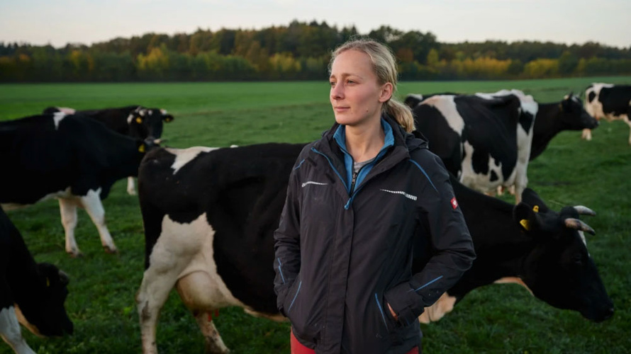 Junge Bäuerin bei den Kühen auf der Weide