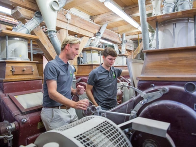 Zwei Müller bedienen das Mahlwerk
