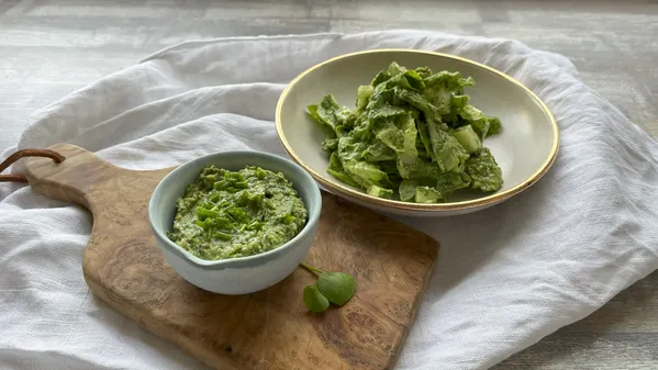 Grünes Kräuterdressing in kleiner Schale auf Holzbrett